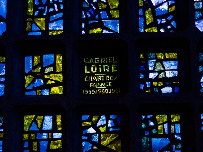 Das Foto zeigt einen Ausschnitt der blau-bunten Fensterwand der Kirche.