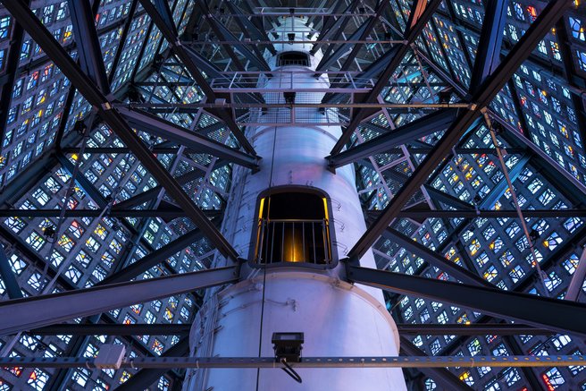 Das Foto zeigt den Glockenturm mit den bunt leuchtenden Fenstern im Inneren.