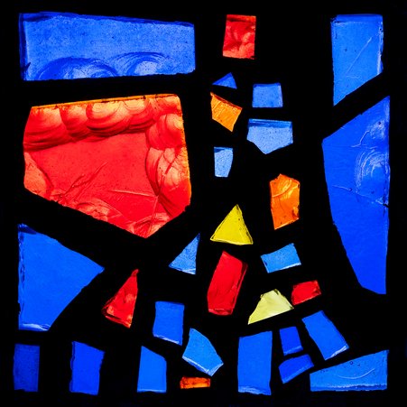 Das Foto zeigt ein einzelnes Fensterglas, das sich aus vielen bunten Glasscherben zusammensetzt. 