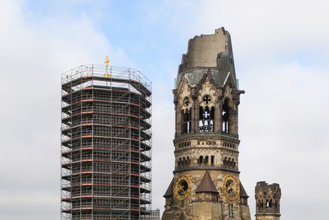 Dieses Foto zeigt den eingerüsteten neuen Glockenturm neben dem alten Turm der Kirchenruine.