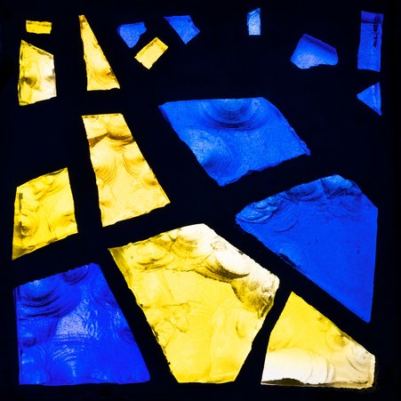 Das Foto zeigt ein einzelnes Fensterglas, das sich aus vielen bunten Glasscherben zusammensetzt. 